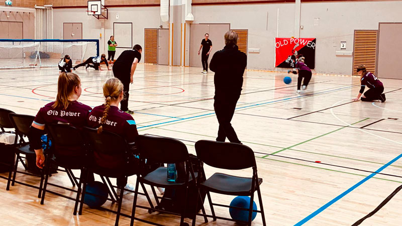 Old Powerin pelaajia kentällä pelaamassa. Etualalla vaihtopenkki.