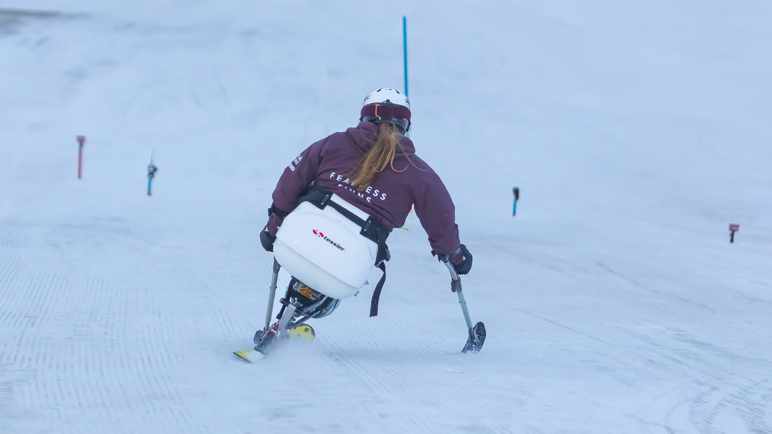 Nette Kiviranta laskemassa mäkeä alas alppihiihtokelkallaan. Kuva otettu takaapäin. 