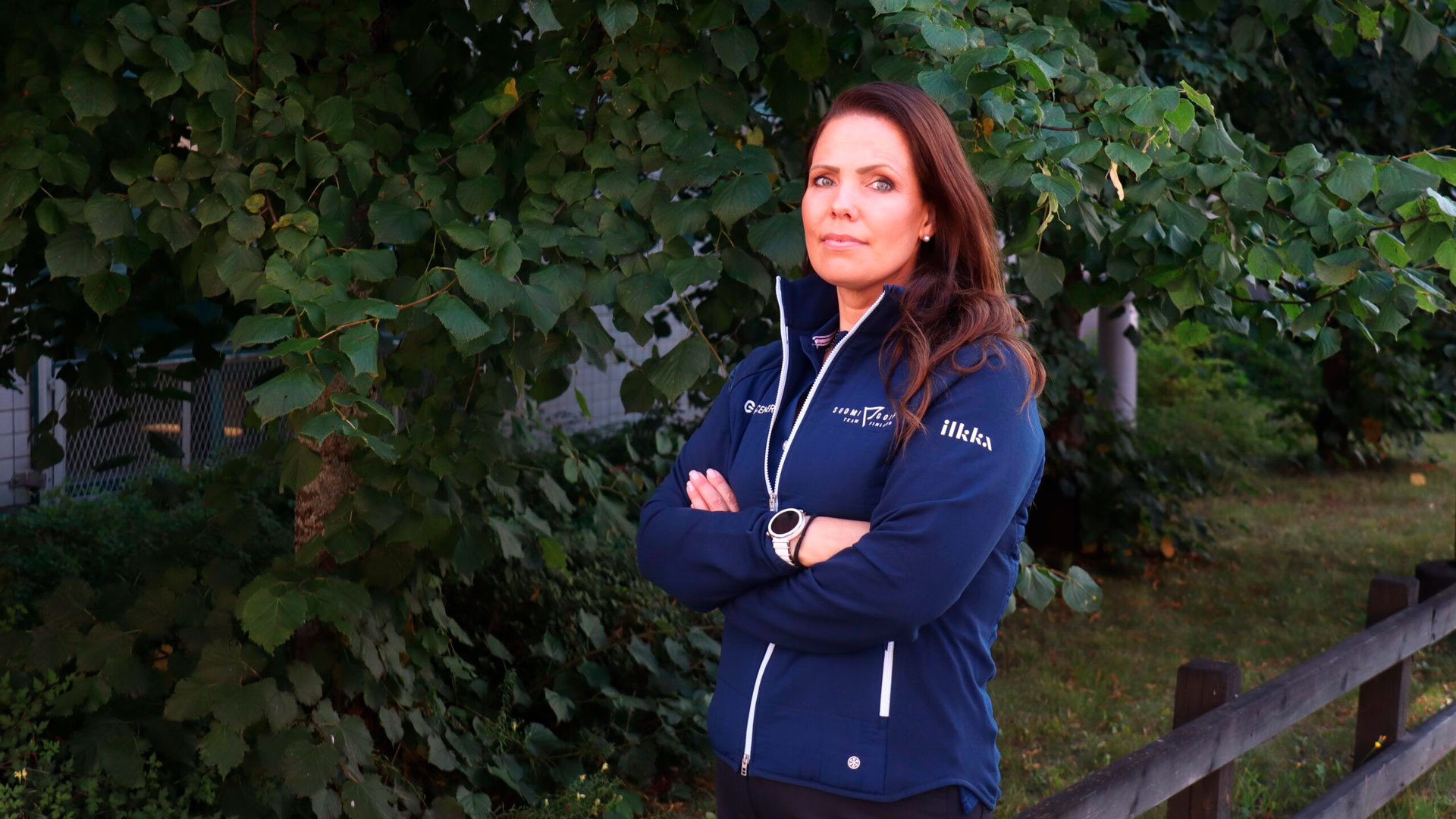 Rosa Svahn poseeraamassa kameralle sinisessä Golfliiton vaatetuksessa ulkona lehtipuun vieressä.
