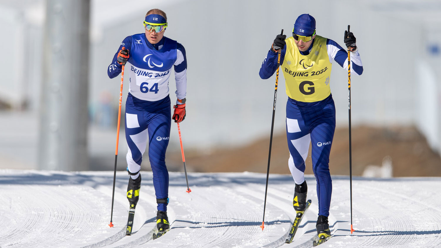 Inola ja opashiihtäjä hiihtävät rinnakkain ylös rinnettä kameraa kohti.
