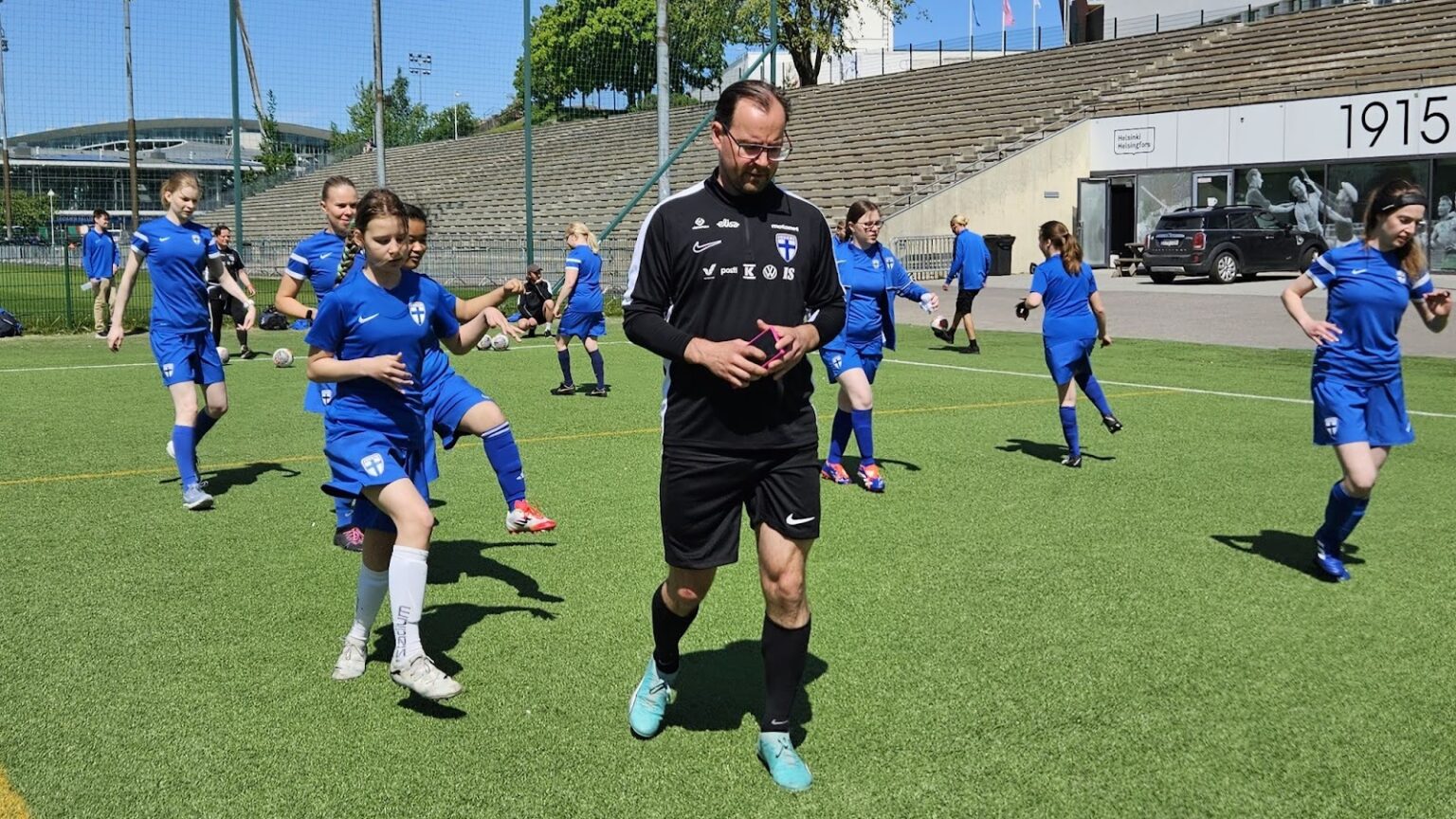 Laurell astelee kentällä harjoitusta tekevien pelaajien keskellä mustassa verkka-asussa.