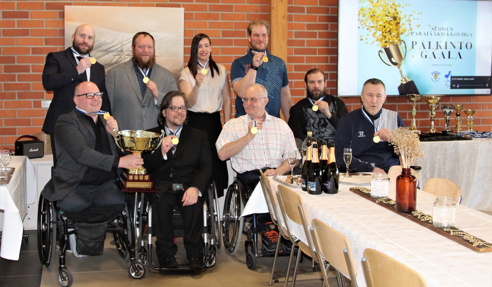 Parajääkiekkoliigan pelaajia mitalein ja pokaalin palkittuna yhteiskuvassa juhlatamineissa.