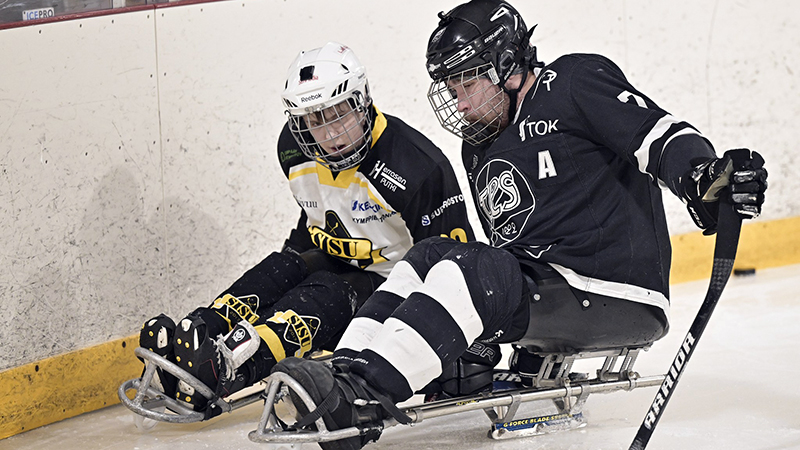 Parajääkiekkoilijat kamppailemassa kiekosta. SISUn ja TPSn pelaajat.