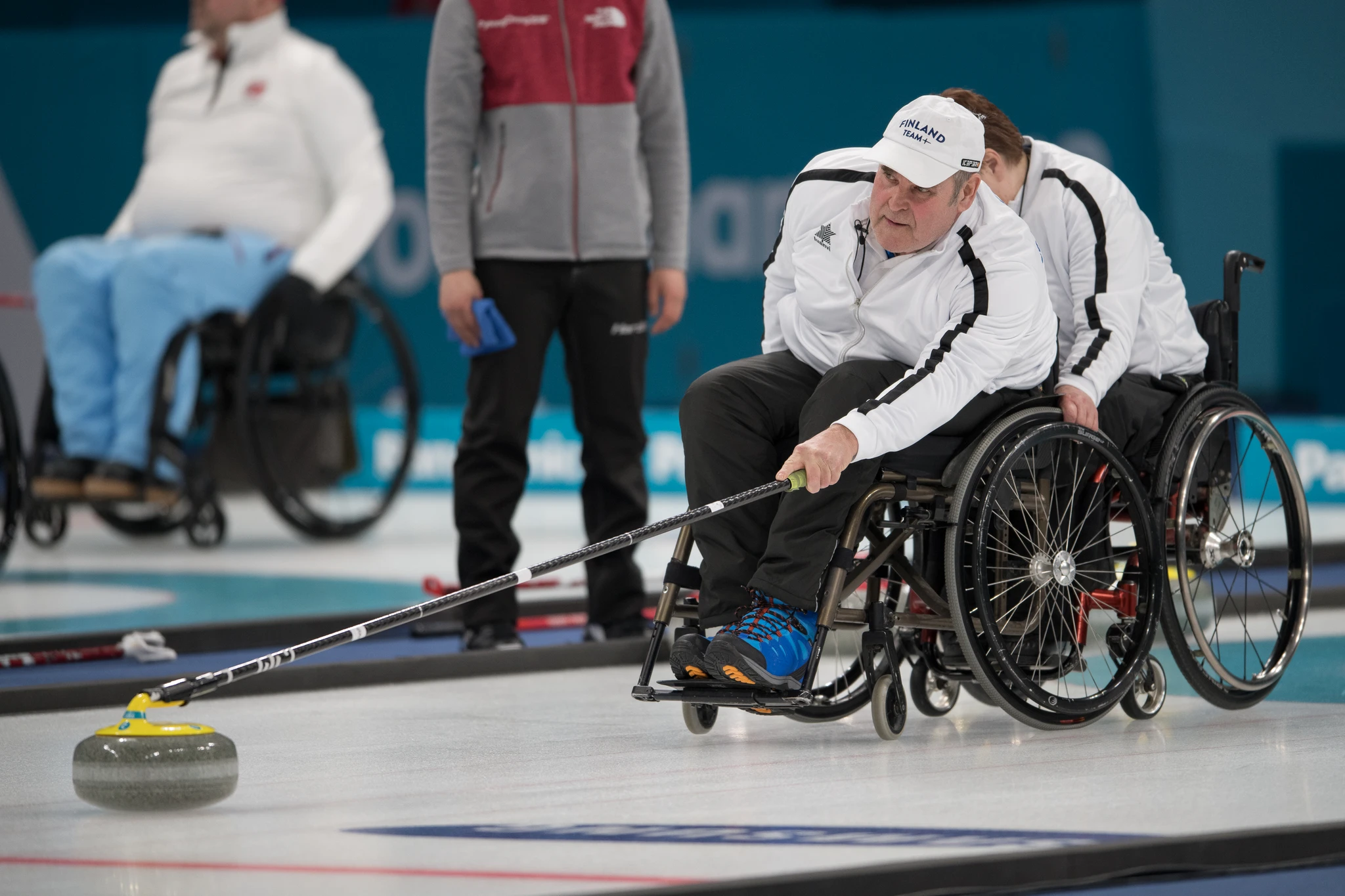 Suomalaispelaaja työntämässä curling-kiveä.