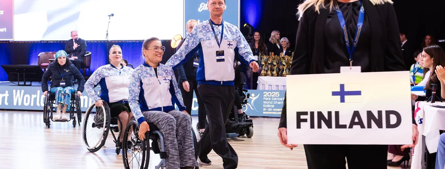 Suomen joukkuelaisia avajaiskulkueessa iloisena.