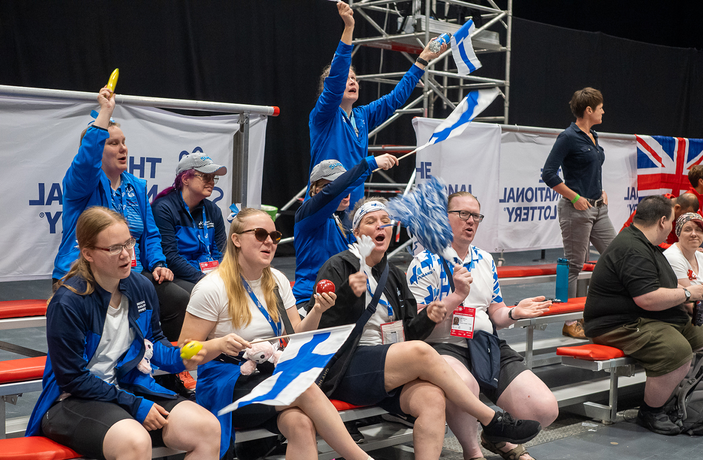 Suomen fanit yleisössä tuulettamassa Suomen lippujen kanssa.