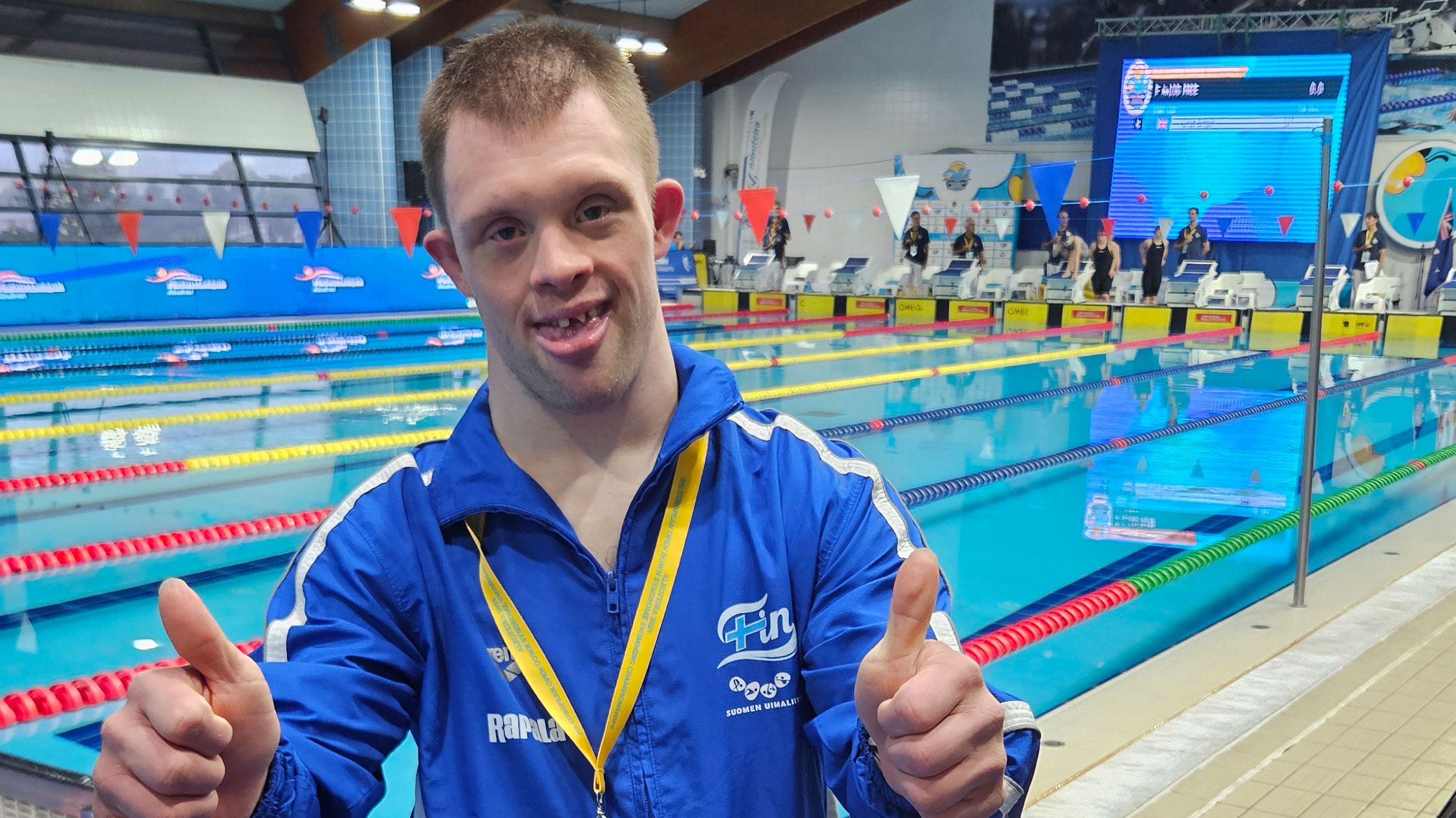 Aleksi Kaidesoja hymyilee altaan reunalla mitali kaulassaan.