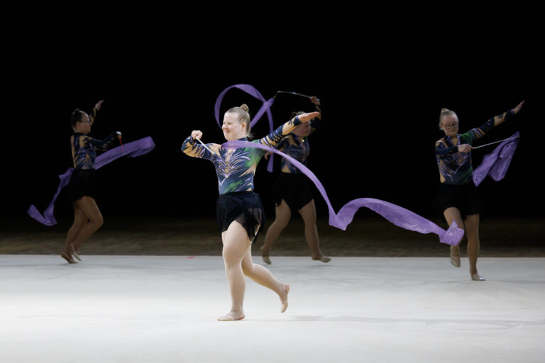 Special Olympics -voimistelijoita voimistelemassa violettien nauhojen kanssa. Myös kisapuvuissa violettia.