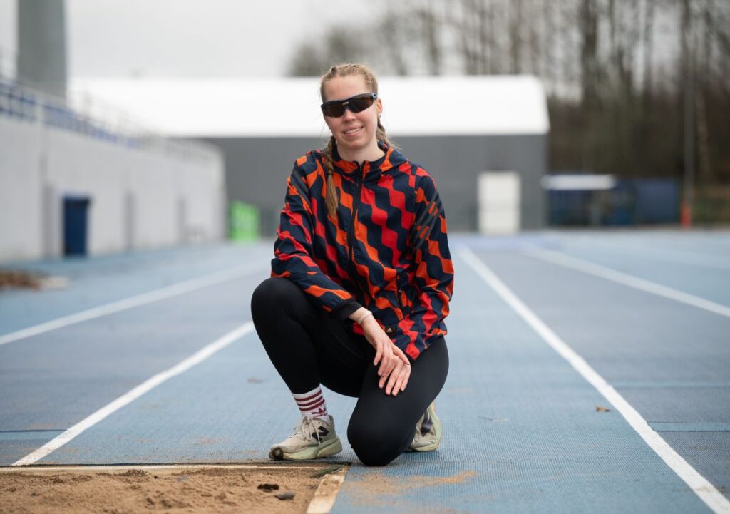 Iida Lounela poseeraamassa puolipolviasennossa pituushyppyalueen vieressä.