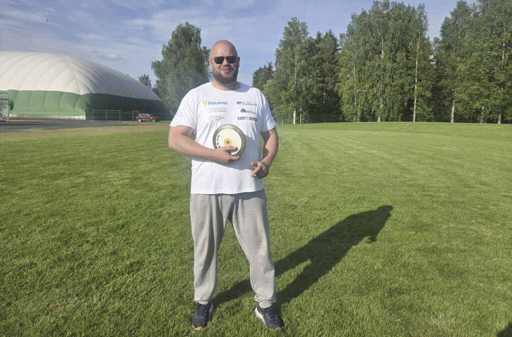 Teijo Kööpikkä poseeraamassa kameralle kiekon kanssa nurmialueella.