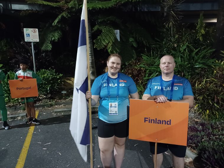 Nea Tilli ja Jani Tissari poseeraamassa kameralle Suomen lipun ja kyltin kanssa.