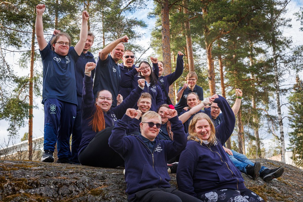Athlete Leaderit iloitsemassa kalliolla metsämaisemassa.