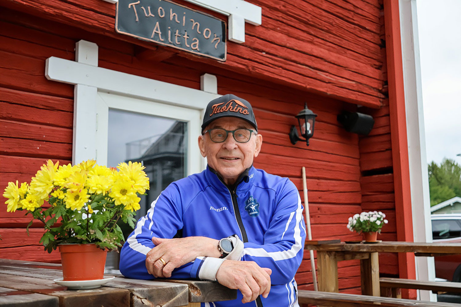 Pertti Sankilampi hymyilemässä kameralle punaisen puurakennuksen edessä Tuohinon tilalla.